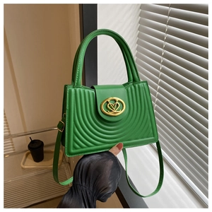 Detail van groene gewatteerde handtas met gouden V-logo en golvende textuur