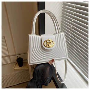 Detail van de witte vintage handtas met gouden ovale logoclaps en gestructureerd reliëf