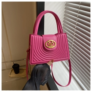 Detail van roze lederen handtas met gouden hartsluiting en boogvormige stiksels