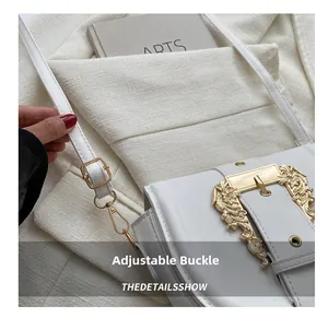 Detail of adjustable buckle and ornate gold baroque buckle on white leather saddle bag