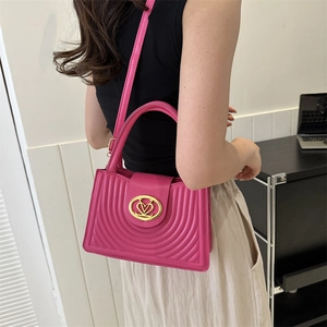 Magenta geplooide crossbodytas met hartsluiting en metalen ketting in lifestyle-omgeving