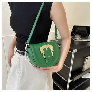 Side view of a green leather saddle bag featuring a large golden baroque engraved buckle