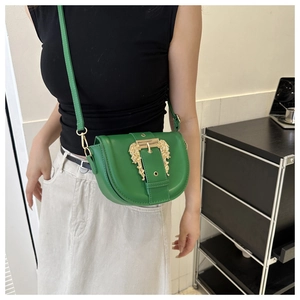 Detail of green saddle bag showing intricate gold baroque buckle and adjustable strap