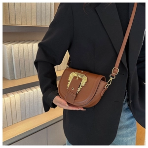 Detail of dark brown saddle bag featuring a large golden baroque relief buckle and strap