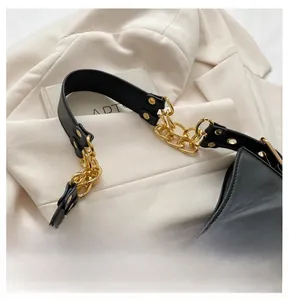 Close-up of black leather underarm bag with decorative gold chain and metallic buckle
