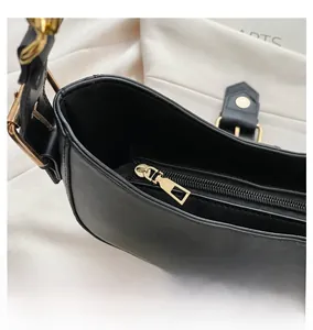 Top detail of black leather handbag featuring premium gold metal zipper and smooth texture
