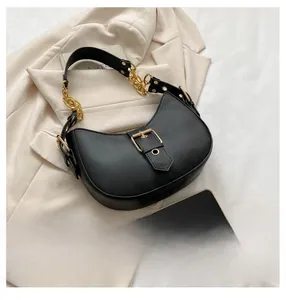 Detail of black faux leather crescent saddle bag with gold metal buckle and chain strap