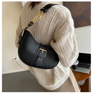 Detail of black matte crescent hobo bag with gold metal buckle and chain strap detailing