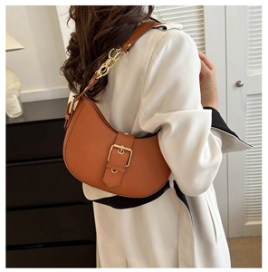 Détail d'un sac demi-lune marron caramel avec boucle dorée et bandoulière à chaîne
