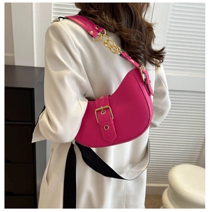 Detail of rose pink crescent bag with golden chunky chain worn on a white suit jacket