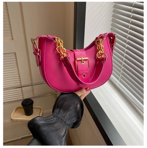 Detail of bright pink crescent bag with chunky gold chain and metallic buckle strap