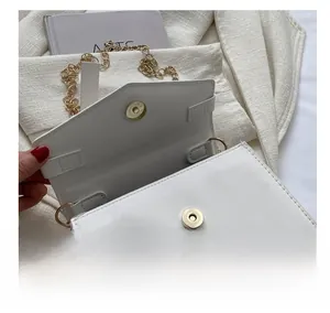 Close-up of the gold magnetic buckle and internal hardware of the white leather bag