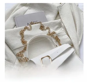Close-up of white leather handbag with golden square buckle and fine chain strap