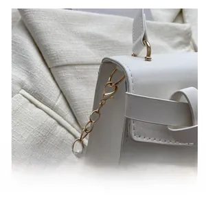 Détail du mini sac blanc en cuir avec chaîne dorée et fermoir mousqueton doré