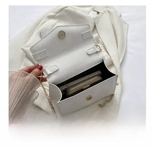 Detail shot of white chain bag interior holding a smartphone and wallet on a blazer