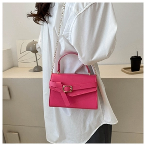 Detail of trendy magenta PU leather crossbody bag with golden chain and top handle