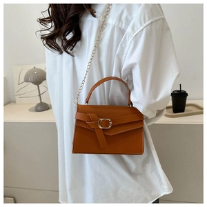 Sac bandoulière marron-orange chic avec chaîne dorée porté par un mannequin en décor épuré