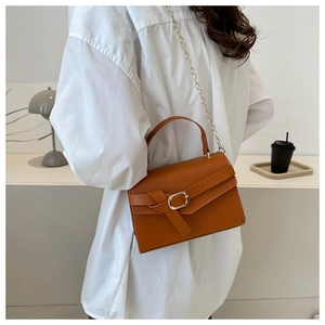 Sac bandoulière marron en similicuir avec chaîne et poignée porté par un mannequin