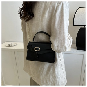Vue détaillée d'un sac à bandoulière noir avec chaîne dorée porté par un mannequin