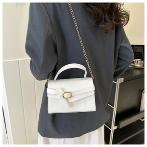 Gros plan du sac bandoulière blanc verni avec boucle dorée et détail de la chaîne