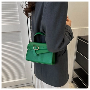 Détail d'un sac bandoulière vert vif avec une chaîne dorée et une boucle décorative