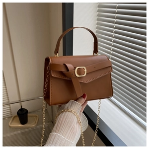 Détail du sac bandoulière en cuir PU marron avec boucle décorative et chaîne dorée