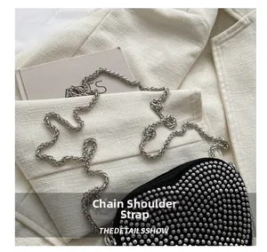 Close-up of heart-shaped black crossbody bag with silver rhinestones and chain strap