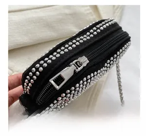 Close-up of smooth silver zipper and metal chain on black studded crossbody bag