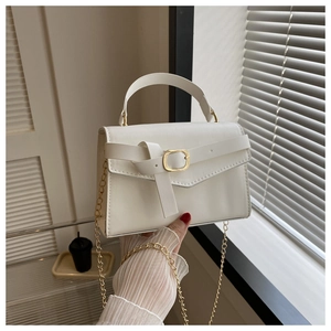 Détail du sac bandoulière crème avec une boucle carrée dorée et une bandoulière en chaîne