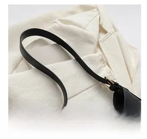 Detail of black woven leather shoulder strap with elegant gold metal buckle and hardware