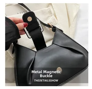 Close-up of black leather half-moon bag featuring a secure golden magnetic buckle closure
