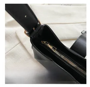 Close-up of smooth golden metal zipper and black leather texture on stylish handbag