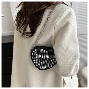 Detail of heart-shaped crossbody bag with silver studs and metal chain strap