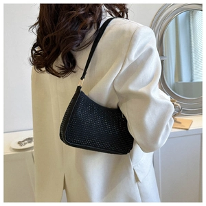 Modella che indossa una borsa baguette nera con strass sulla spalla con un blazer bianco