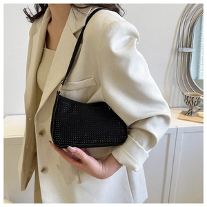 Vista laterale della borsa baguette con strass neri abbinata a un blazer beige elegante