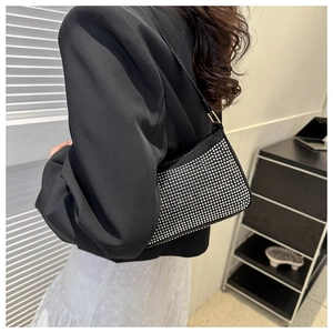 Primo piano di una borsa baguette nera con strass indossata da una modella alla moda