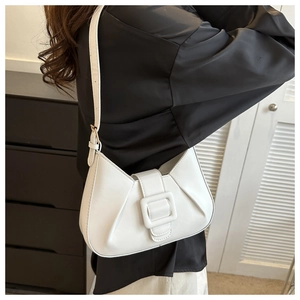 Close-up of white pleated shoulder bag with square buckle on a female model