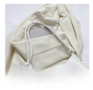 Detail of off-white leather shoulder bag with round buckle on elegant tweed blazer