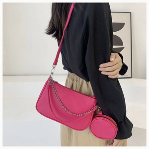Detail of magenta rectangular crossbody bag with round coin purse and silver chain link