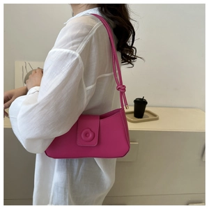 Détail latéral du sac baguette en cuir rose rouge avec boucle magnétique et bandoulière