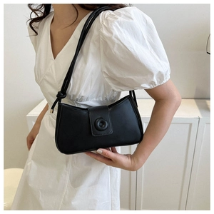 Close-up of minimalist black leather underarm bag with round decorative buckle detail