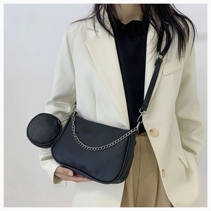 Détail d'un sac bandoulière noir avec chaîne argentée et petit porte-monnaie amovible