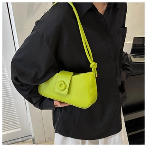 Close-up of neon green leather underarm bag with knot detail and circular decoration