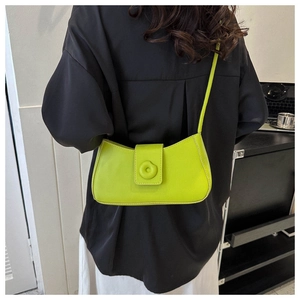 Detail showing bright neon green shoulder bag worn with contrast black outfit for daily commute