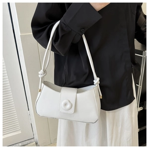 Detail of white leather shoulder bag featuring floral buckle and knotted strap accents