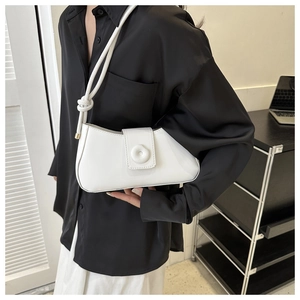 Detail view of a white minimalist shoulder bag with unique knot strap and round buckle design
