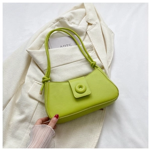 Détail du sac sous le bras en cuir vert avec rabat magnétique et bandoulière nouée