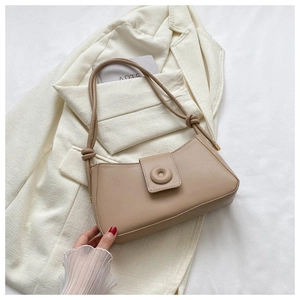 Détail du sac baguette beige avec bandoulière nouée et boucle ronde sur veste