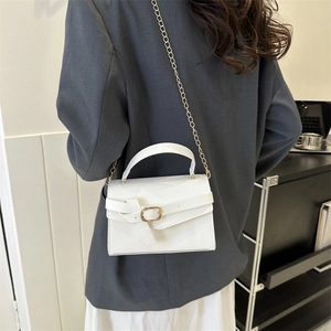 Sac bandoulière blanc minimaliste avec chaîne dorée porté par un mannequin de mode