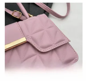 Detalle del bolso bandolera rosa acolchado con costuras triangulares y herrajes dorados
